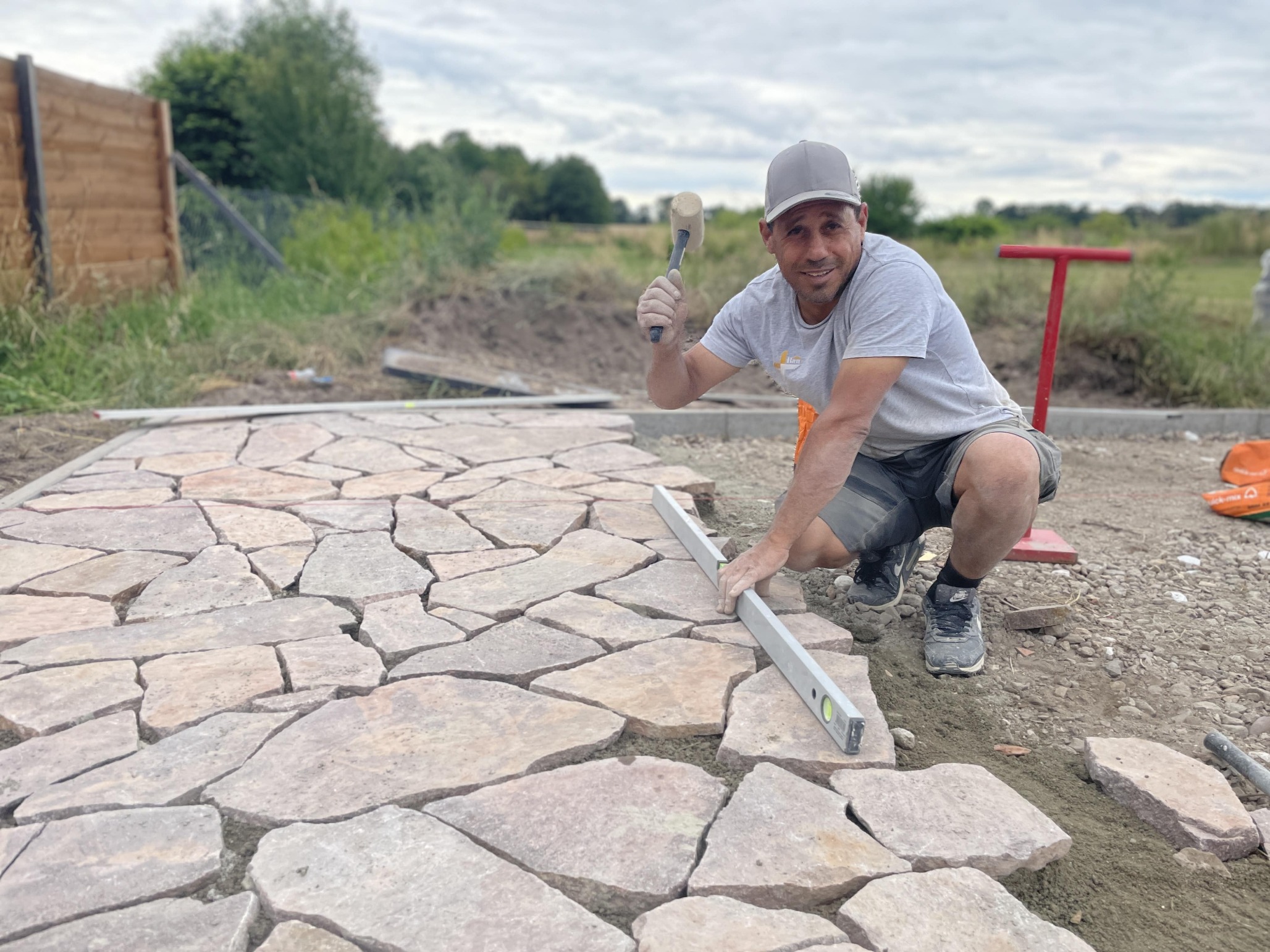 Natursteinplatten werden im polygonalen Verband auf einer Gartenfläche in Berlin verlegt