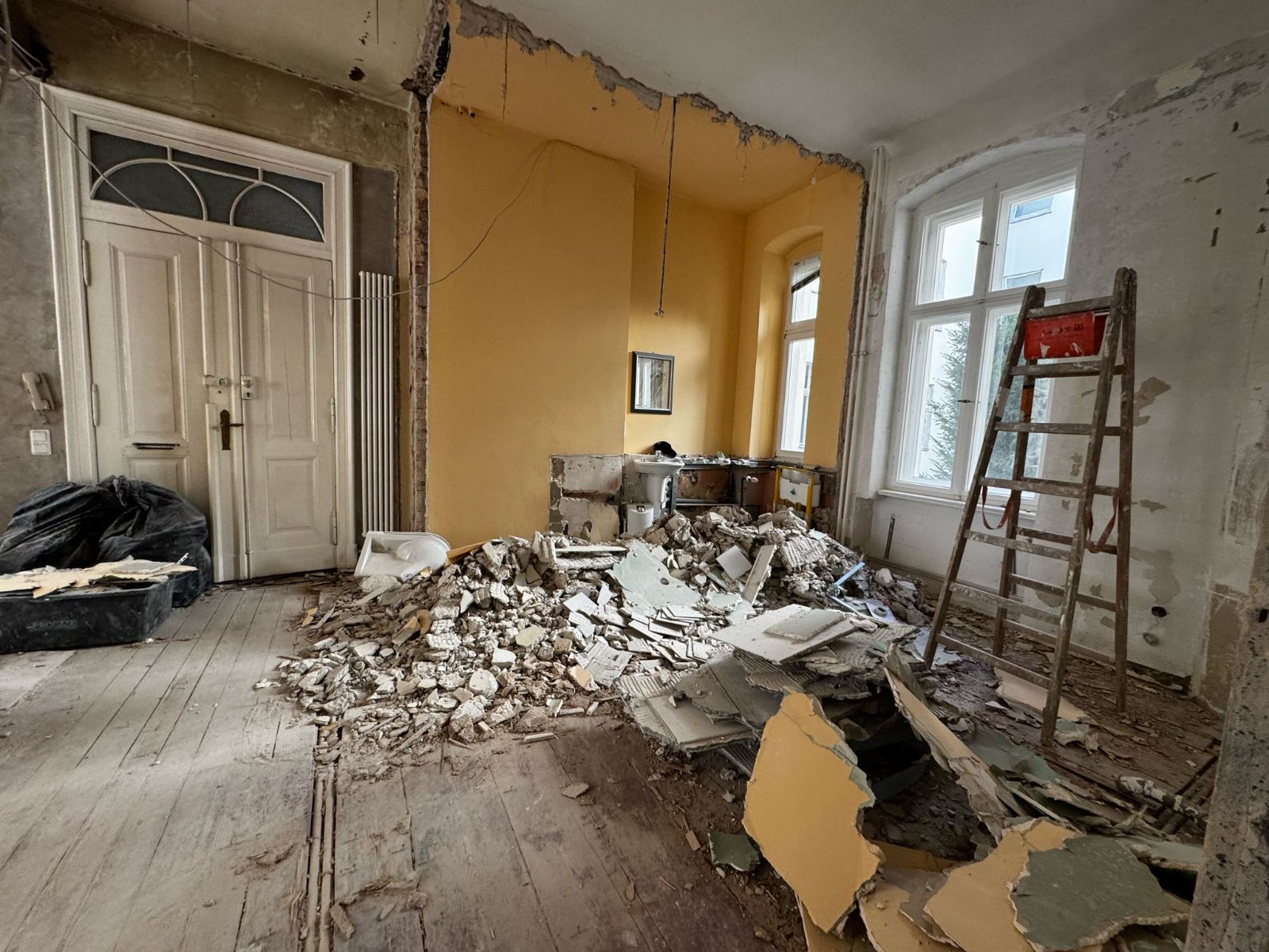 Abrissarbeiten in einer Berliner Altbauwohnung: Wand zurückgebaut, Schutt auf dem Dielenboden